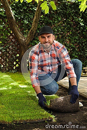 Young man laying grass sod on ground Stock Photo