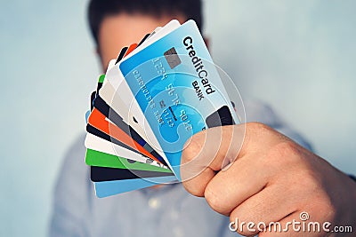 Young man in light blue shirt showing many types of credit cards. Businessman in casual wear holding in hand various payment cards Stock Photo