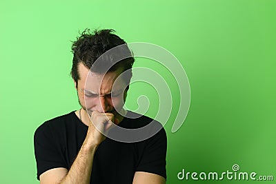 Young man on a light green wall background. Emotion of chagrin or grief Stock Photo