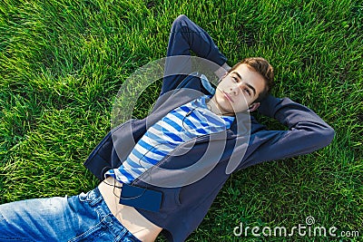 Young man listening music from smart phone on the grass in the park. Stock Photo