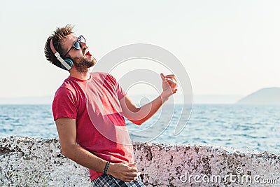 Young man listening to the music on headphones playing imaginary guitar Stock Photo