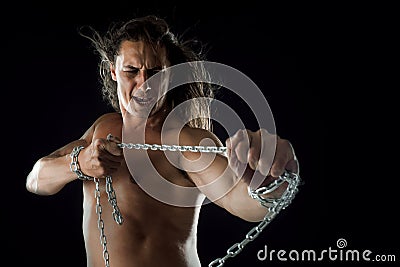 Young man with long hair breaks the iron chain. Strong. Concept of resistance Stock Photo