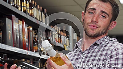 Young man looking confused while choosing wine Stock Photo