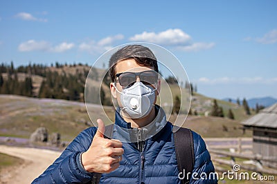 Young man in mask and sunglasses walking outside Stock Photo