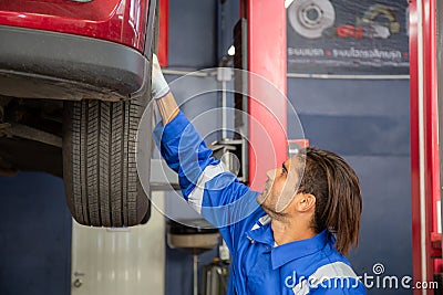 Young man is mechanic repair tires wheel car in the garage with professional, auto service. Stock Photo