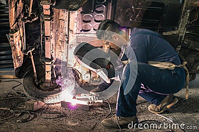 Young man mechanic worker repairing old vintage car body Stock Photo