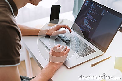 Young man mobile developer, programmer writes program code on a laptop Stock Photo
