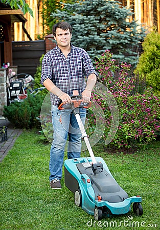 Young man mowing grass at house backyard Stock Photo