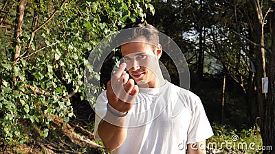 Young man in nature calling closer with hand gesture Stock Photo