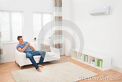 Young Man Operating Air Conditioner Stock Photo