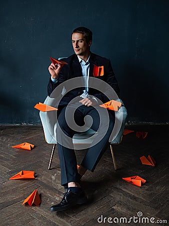 Young man and orange paper planes. Dreams of traveling and flying. Stock Photo