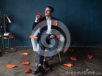 Young man and orange paper planes. Dreams of traveling and flying Stock Photo