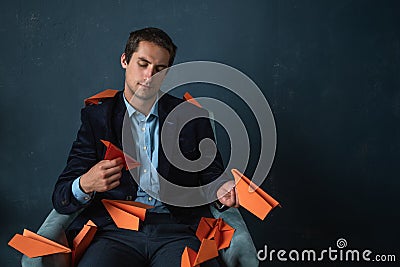 Young man and orange paper planes. Dreams of traveling and flying Stock Photo