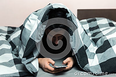 Young man in pajamas using a cellphone Stock Photo