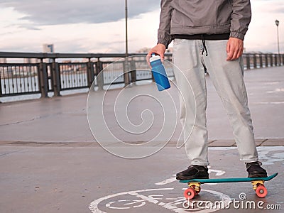 Young man on a penny board with a reusable plastic bottle in his hands Stock Photo