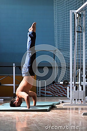 Young man performing handstand in fitness studio Stock Photo