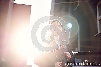 Young man with phone in hands on walk in city against backdrop of modern buildings. Stock Photo