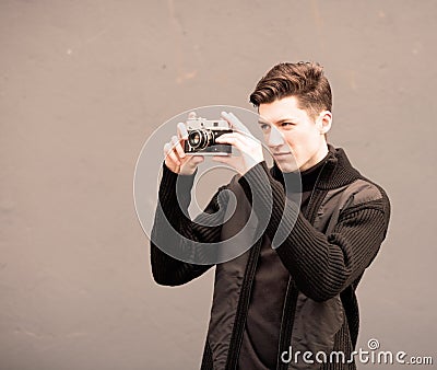 The young man photographs model the vintage camera at a wall Stock Photo