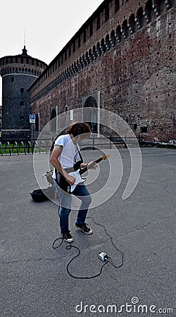 Young man plaing rock solo on guitar near Castello Sforzesco. Milan Editorial Stock Photo