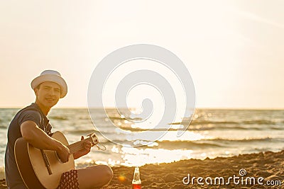 Young man play guitar on the beach and enjoy in sunset Stock Photo