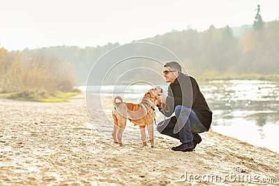 Young man playing with dog near the river Stock Photo