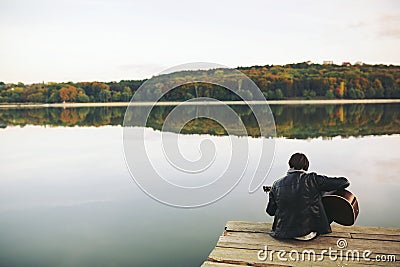 Young man playing on guitar at the lake Stock Photo