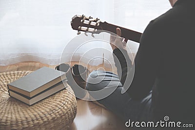 Young man playing the guitar after reading a book. Stock Photo