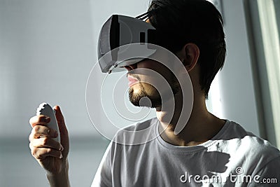 A young man plays a virtual game in VR glasses. home leisure on self-isolation at home. The virtual reality. portrait of handsome Stock Photo