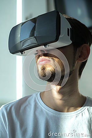 A young man plays a virtual game in VR glasses. home leisure on self-isolation at home. The virtual reality. portrait of handsome Stock Photo