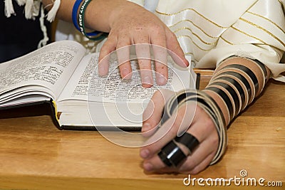 A young man pointing at a phrase in a bible book sefer torah, while reading a pray at a Jewish ritual Stock Photo