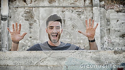 Young man popping out from behind a small wall Stock Photo
