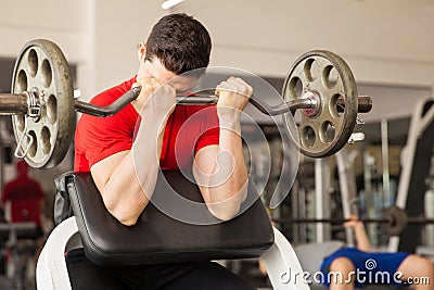 Young man in a preacher bench at the gym Stock Photo