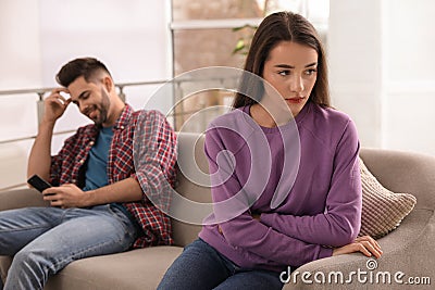 Young man preferring smartphone over his girlfriend on couch Stock Photo
