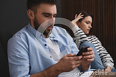 Man preferring smartphone over his girlfriend at home. Relationship problems Stock Photo