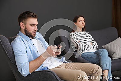 Young man preferring smartphone over his girlfriend at home. Relationship problems Stock Photo