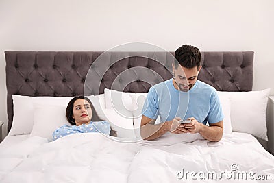 Young man preferring smartphone over his girlfriend at home Stock Photo