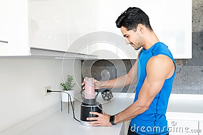 Young Man Preparing Healthy Drink In Kitchen Stock Photo