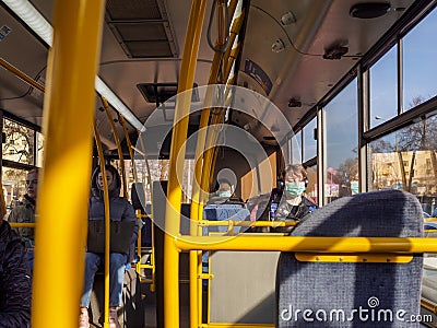 A young man in a protective mask and headphones sits on the bus Editorial Stock Photo