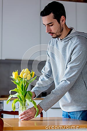 Young man put in yellow tulips in glass Stock Photo