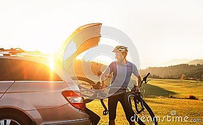 Young Man puting his bicycle in the trunk of a car Stock Photo