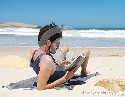 Young man reading book on secluded beach Stock Photo