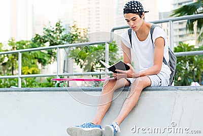 Young man reading at the skateboard park. Stock Photo