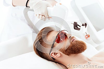 Young man receiving laser skin care on face Stock Photo