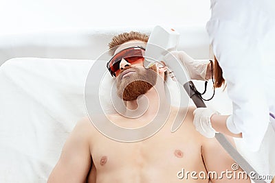 Young man receiving laser skin care on face isolated on white Stock Photo