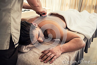 Young man relaxing during traditional massage with hot stones Stock Photo