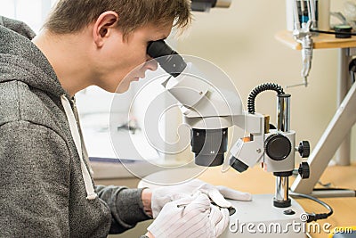 Young man repairing computer components in service center using microscope. Electronics repair and fix service concept. Stock Photo