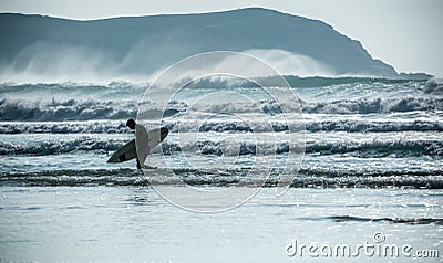 Young man returns ashore after good days surfing, Fistral beach, Newquay, Cornwall Editorial Stock Photo