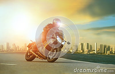 young man riding big motorcycle leaning on sharp curve with urban building background Stock Photo