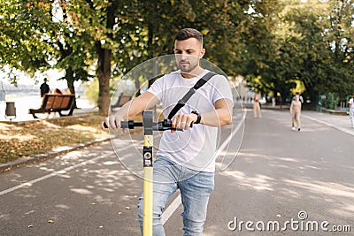 Young man riding an electric scooter on a meeting. Ecological transportation concept. Handsome man outdoors with e Stock Photo