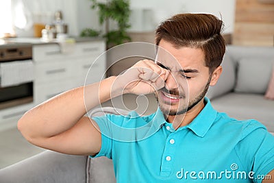 Young man rubbing eye at home Stock Photo